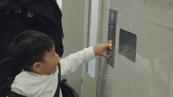 亚洲男婴按下按钮打开电梯门