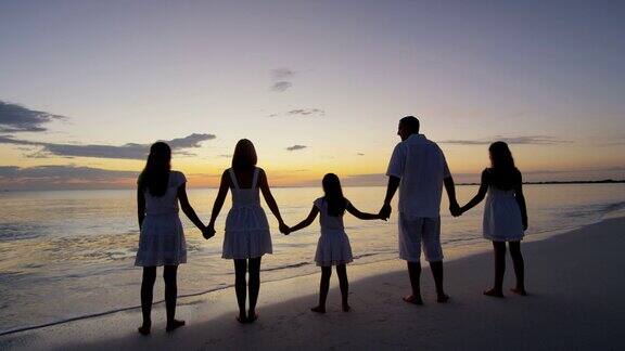 在海滩上落日的剪影白种人家庭