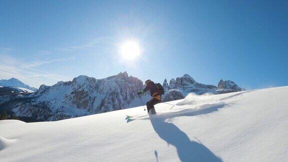 跟随特写:快乐的滑雪者有乐趣滑雪在一个阳光明媚的冬天在雪山的backcountry极速免费滑雪滑雪者在意大利白云石山滑雪胜地的雪道上骑着新鲜的粉末雪