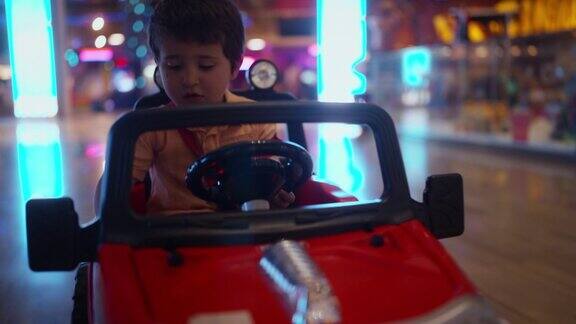 在游乐场里小男孩骑着电池驱动的玩具车