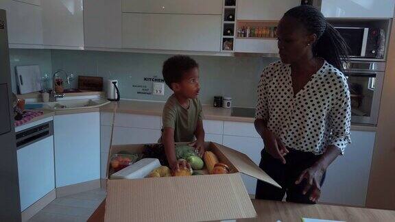 非洲妇女和她的儿子从盒子里拿出杂货