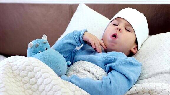 孩子咳嗽男孩用围巾围在脖子上宝宝用电子温度计测温度孩子用压头的方式躺在床上感冒