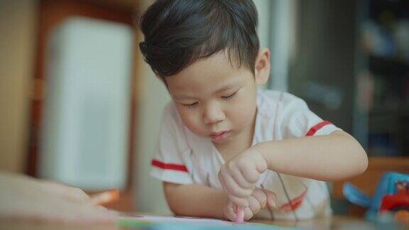 一位可爱的小男孩在客厅里用彩色笔画画