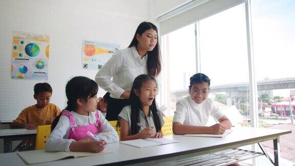 老师在学校的教室里教和检查她的小学生