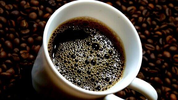 黑咖啡倒进白杯子里堆在一堆烘好的咖啡豆上