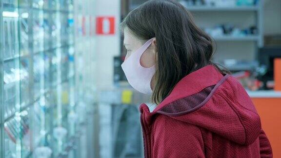 戴着防毒面具的妇女在商店里挑选电子产品