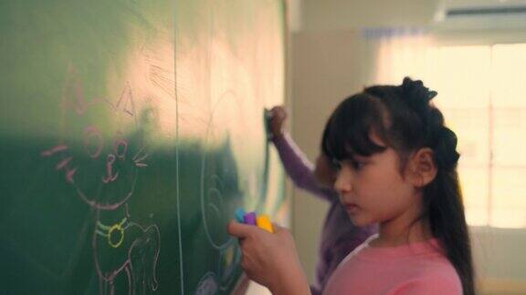小学生在教室里用彩色粉笔在黑板上画画