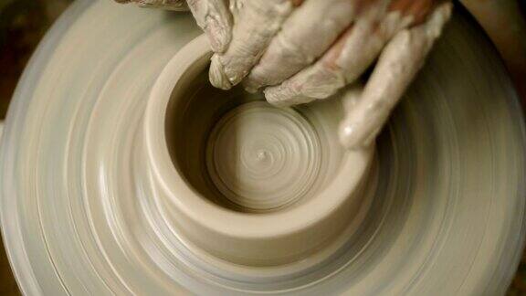 人们用未加工的湿粘土在制陶轮上制作了一个手臂脏兮兮的罐子