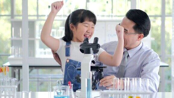 小孩和老师在用显微镜观察