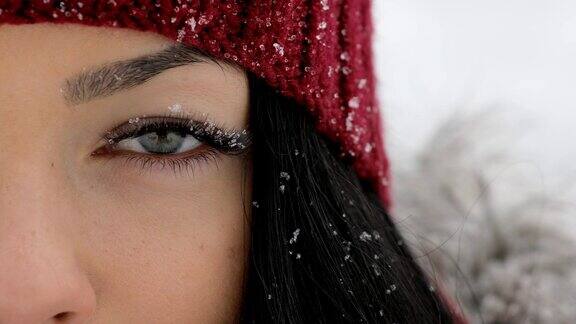 特写的女人睁开她的眼睛与雪在大睫毛