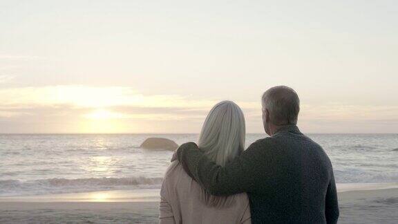 一对夫妇在日落时从岸上看海