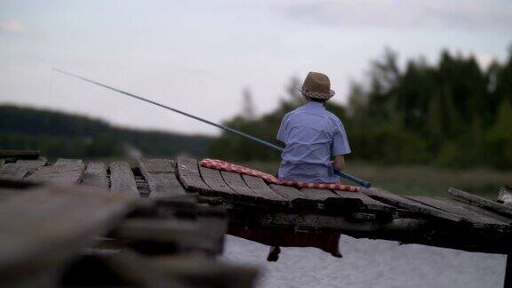 男孩在河边的旧码头上钓鱼在户外