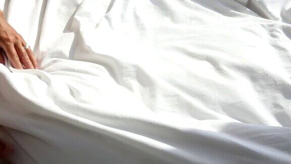 女人把白色毯子扔在床上的特写镜头