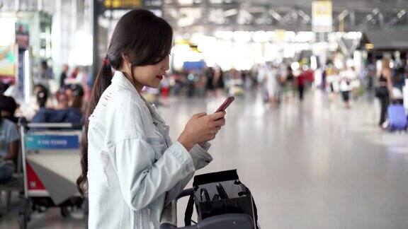 年轻的亚洲女性在机场用智能手机检查航班准备旅行