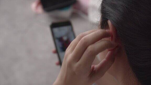 亚洲妇女使用智能手机和搔痒她的耳朵