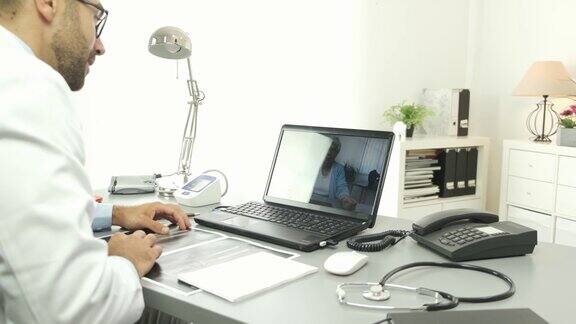 英俊的医生提供远程医疗咨询与资深女病人通过互联网电脑远程医疗诊断4K50fps的视频