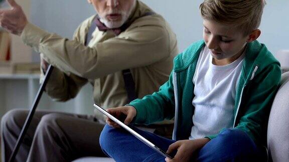 爷爷教训小男孩玩平板电脑游戏批评孩子的行为