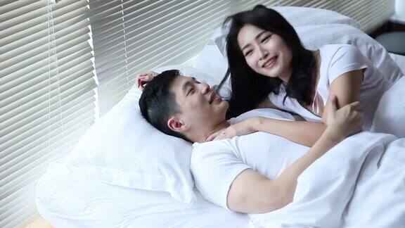 亚洲华人夫妇拥抱在床上睡觉在早上微笑