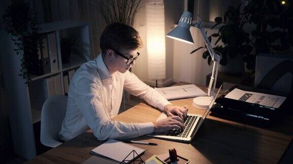 深思熟虑的商人在办公室深夜使用笔记本电脑