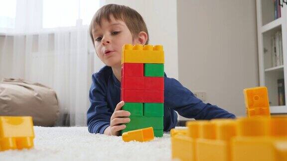 一个小男孩用五颜六色的塑料玩具积木搭起一座高塔儿童教育观念与家庭游戏
