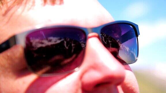 男人戴着墨镜太阳眼镜里的山的倒影