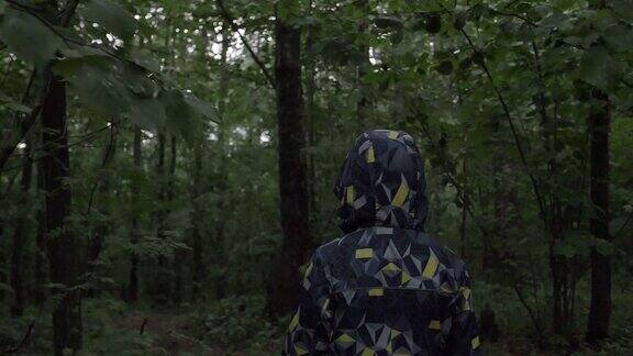 穿夹克戴兜帽的男孩晚上在森林里散步