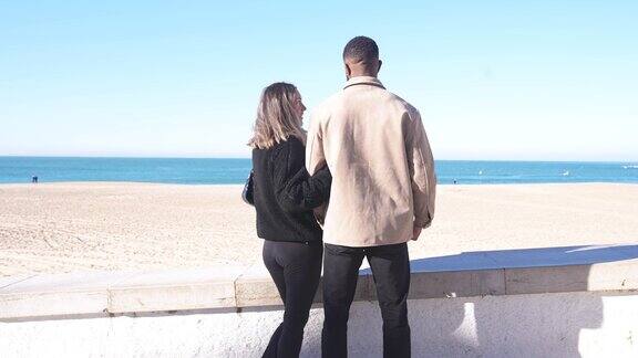 年轻的混血夫妇在度假在海滩上散步