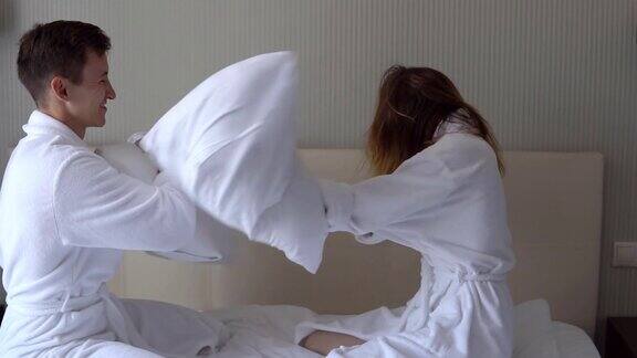 在他的房间里一对穿着白大褂的相爱的年轻夫妇在度蜜月时胡闹在床上用枕头安排打斗慢镜头