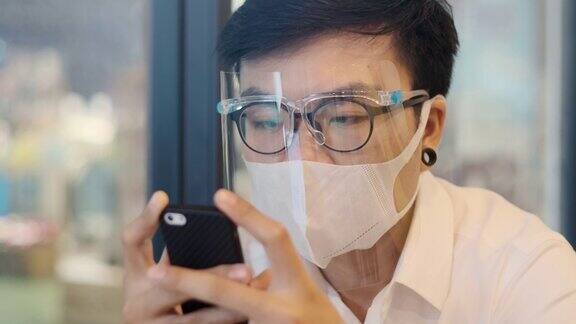 亚洲人戴口罩和面罩使用智能手机