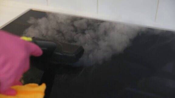 家庭主妇用热蒸汽清洁器清洁黑色陶瓷灶台春天的时间清洗前视图缓慢的运动