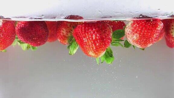 高清:慢动作草莓掉进水里白色背景慢动作
