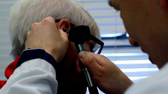 年轻的亚洲男医生在4k诊所用耳镜检查一位老年病人