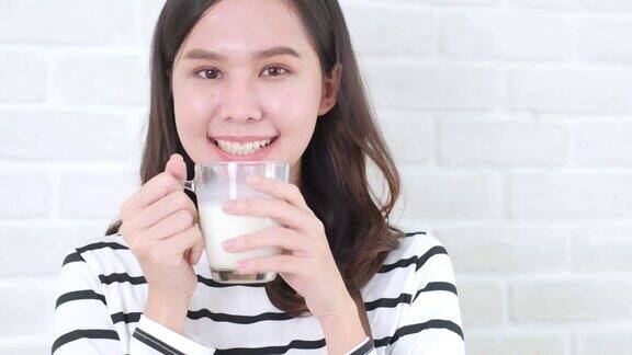 迷人的亚洲女人喝牛奶和微笑在家里近距离面对健康的生活方式