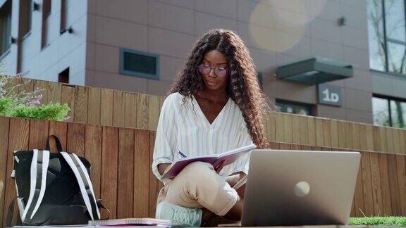 年轻的黑人女性大学生在户外使用笔记本电脑在线学习
