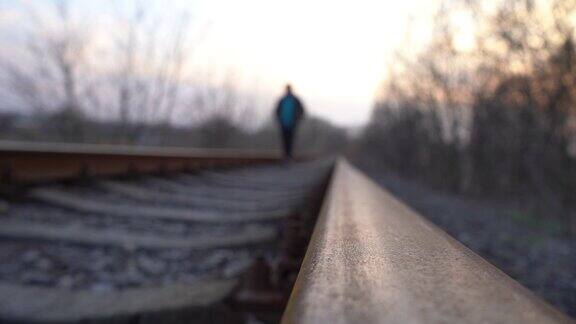 一个男人沿着铁轨走一名难民在铁轨上行走在铁路上行走很危险