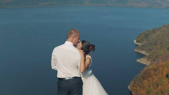 年轻美丽的新婚夫妇一起在海边山上的斜坡上可爱的新郎和新娘慢动作