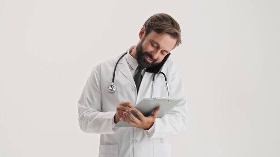 快乐的男人医生与听诊器工作与医疗历史和通话的智能手机