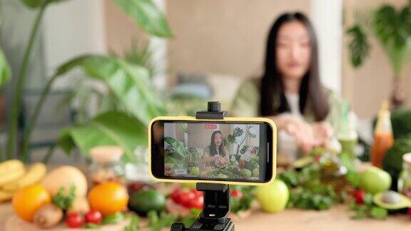 亚洲女性博主在智能手机上录制视频课程介绍如何制作健康沙拉的食谱