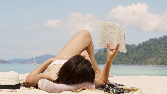 暑假亚洲女人在海滩上读一本书在空闲时间假期
