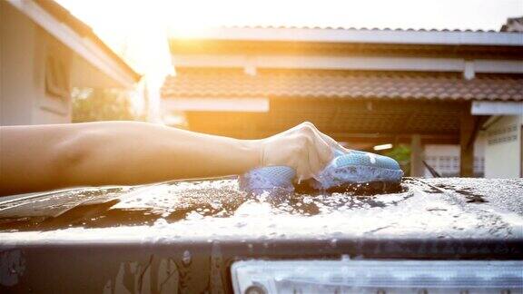 慢镜头特写女子用蓝色海绵清洁汽车的手