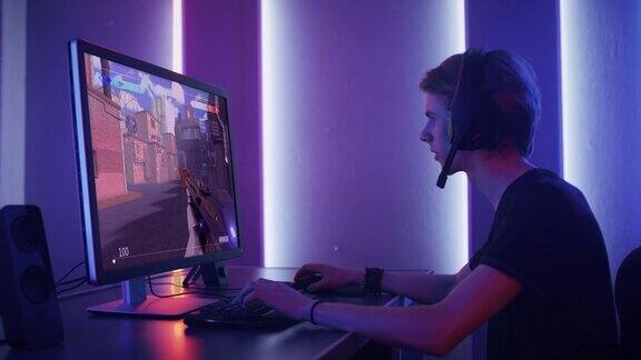 专业电竞玩家熟练地玩3D射击模拟视频游戏与超级行动和有趣的特殊效果在他的电脑上使用耳机与队友交谈网络游戏复古霓虹房间