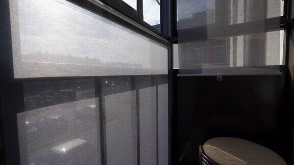 在阳光明媚的日子里公寓阳台窗户上有阴影的灰色滚轴百叶窗