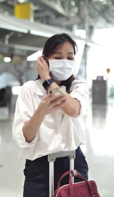 年轻女子穿着衣服在国际机场等待她的航班和使用手机