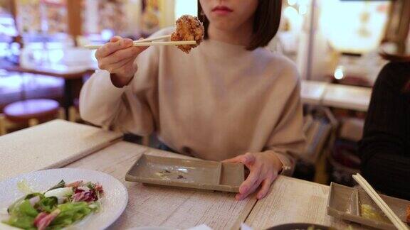 一个年轻的日本女人在居酒屋酒吧吃炸鸡
