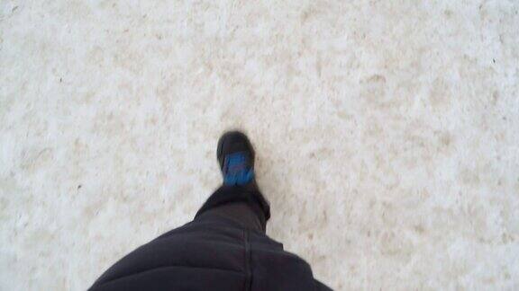 穿着黑色靴子的男人的腿在冬天的雪地里行走观点视频