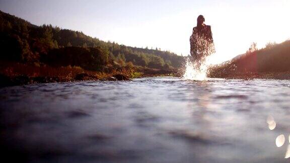 年轻女子赤脚行走在山河中溅水