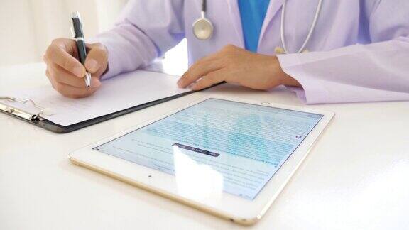 医生在医院使用数字平板电脑和书写医疗图表