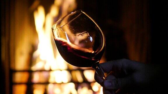 冬天在壁炉前斟着红酒品酒于杯中