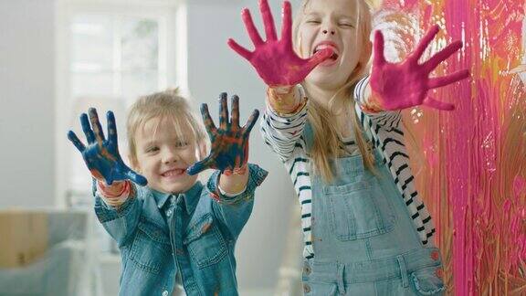 两个有趣的小姐妹展示她们的手蘸了彩色颜料他们是快乐的和笑姐妹关系的目标重新装饰在家里