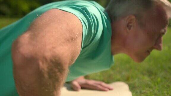 一个阳光明媚的早晨一个金发的成年健身教练在公园里做俯卧撑的特写镜头